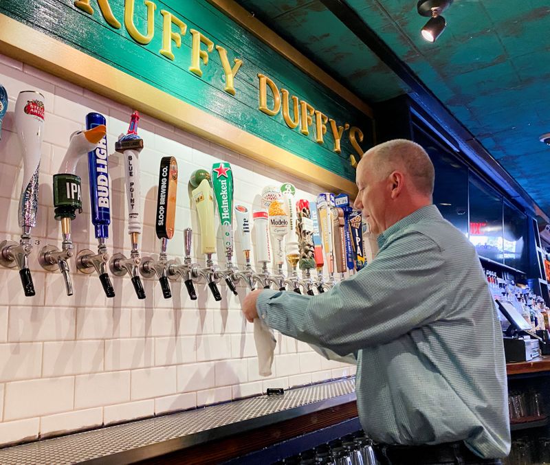 &copy; Reuters. Bar owner Pat Hughes, cleans his beer taps at Scruffy Duffy's, which has been closed for more than a year. in New York, U.S., May 17, 2021.    REUTERS/Roselle Chen