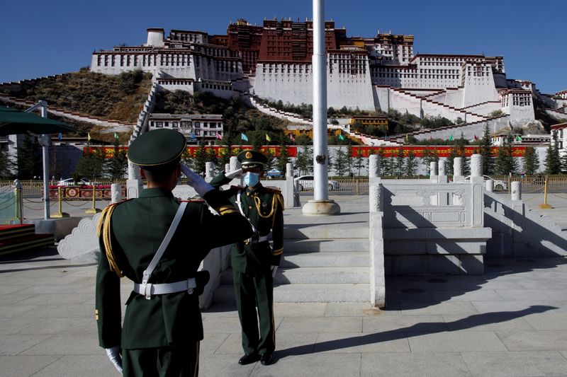 &copy; Reuters. FILE PHOTO: Paramilitary police officers salute during a change of flag duty in front of Potala Palace in Lhasa during a government-organised tour of the Tibet Autonomous Region, China, October 15, 2020.  Picture taken October 15, 2020.  REUTERS/Thomas Pe