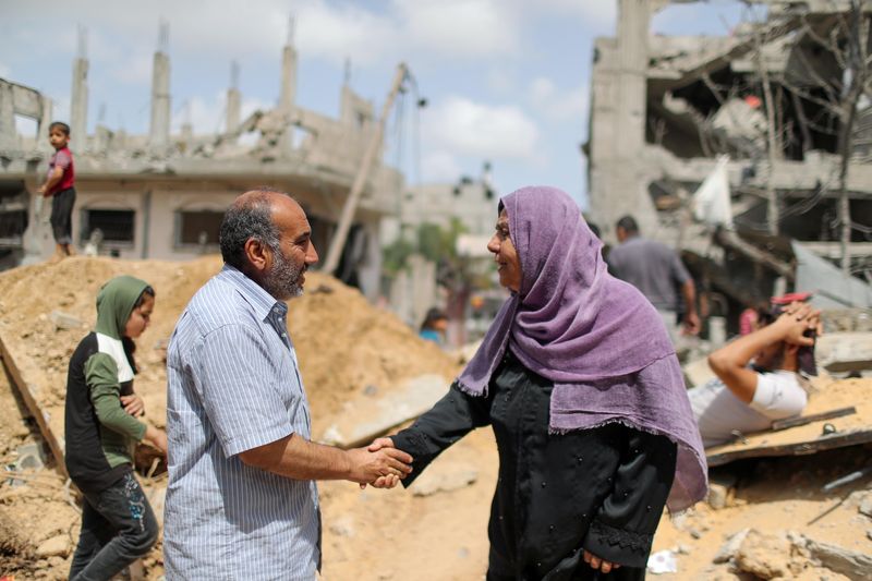 © Reuters. FILE PHOTO: Palestinians shake hands after returning to their destroyed houses following Israel- Hamas truce, in Beit Hanoun in the northern Gaza Strip, May 21, 2021. REUTERS/Mohammed Salem