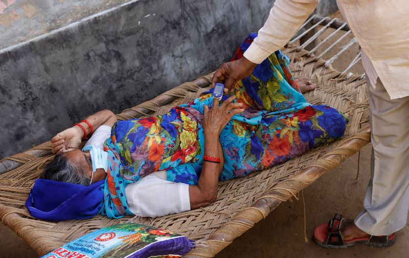 &copy; Reuters. Moorti, 62, a villager suffering from fever rests on a cot as she waits to receive treatment at a clinic set up by a local villager, amidst the spread of the coronavirus disease (COVID-19), in Parsaul village in Greater Noida, in the northern state of Utt