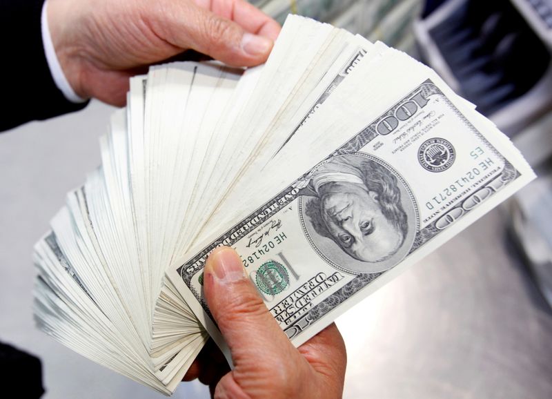 &copy; Reuters. Un uomo con diverse banconote da 100 dollari statunitensi. REUTERS/Jo Yong-Hak