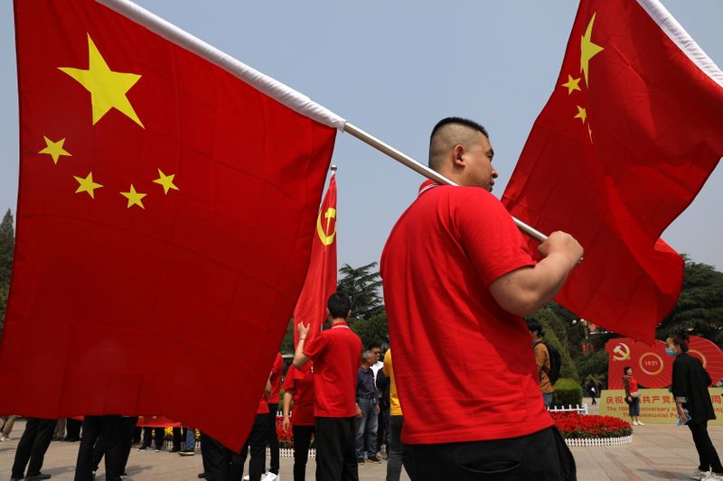 &copy; Reuters. زائر يحمل العلم الصيني أمام القاعة التذكارية للحزب الشيوعي  في شيبايبو يوم 12 مايو أيار 2021. تصوير: تينجشو وانج - رويترز.