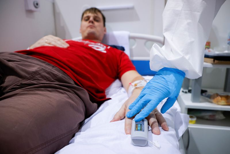 &copy; Reuters. A medical specialist puts a pulse oximeter on a patient's finger to check his blood oxygen level in a ward at the Krylatskoye Ice Palace, which was converted into a temporary hospital for people suffering from the coronavirus disease (COVID-19), in Moscow