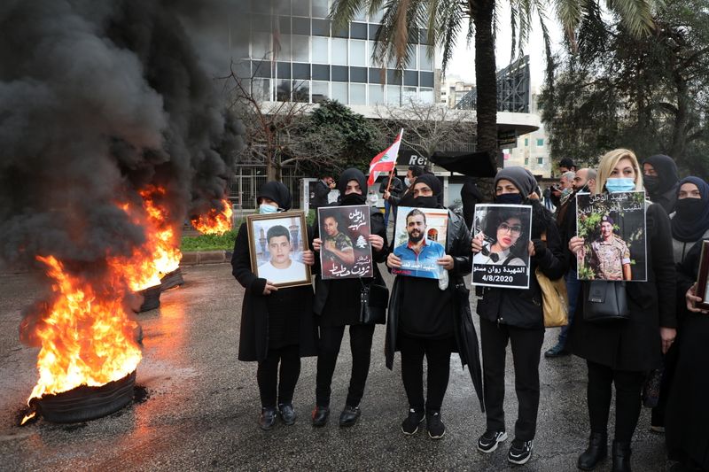 &copy; Reuters. أقارب ضحايا تفجير مرفأ بيروت يرفعون صور للضحايا بجوار إطارات مشتعلة في احتجاج أمام قصر العدالة في العاصمة اللبنانية يوم 19 فبراير شباط 2021. تص