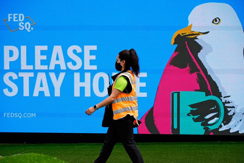 &copy; Reuters. FILE PHOTO: An essential worker walks past a 'Please Stay Home' sign on the first day of a five-day lockdown implemented in the state of Victoria in response to a coronavirus disease (COVID-19) outbreak in Melbourne, Australia, February 13, 2021.  REUTERS